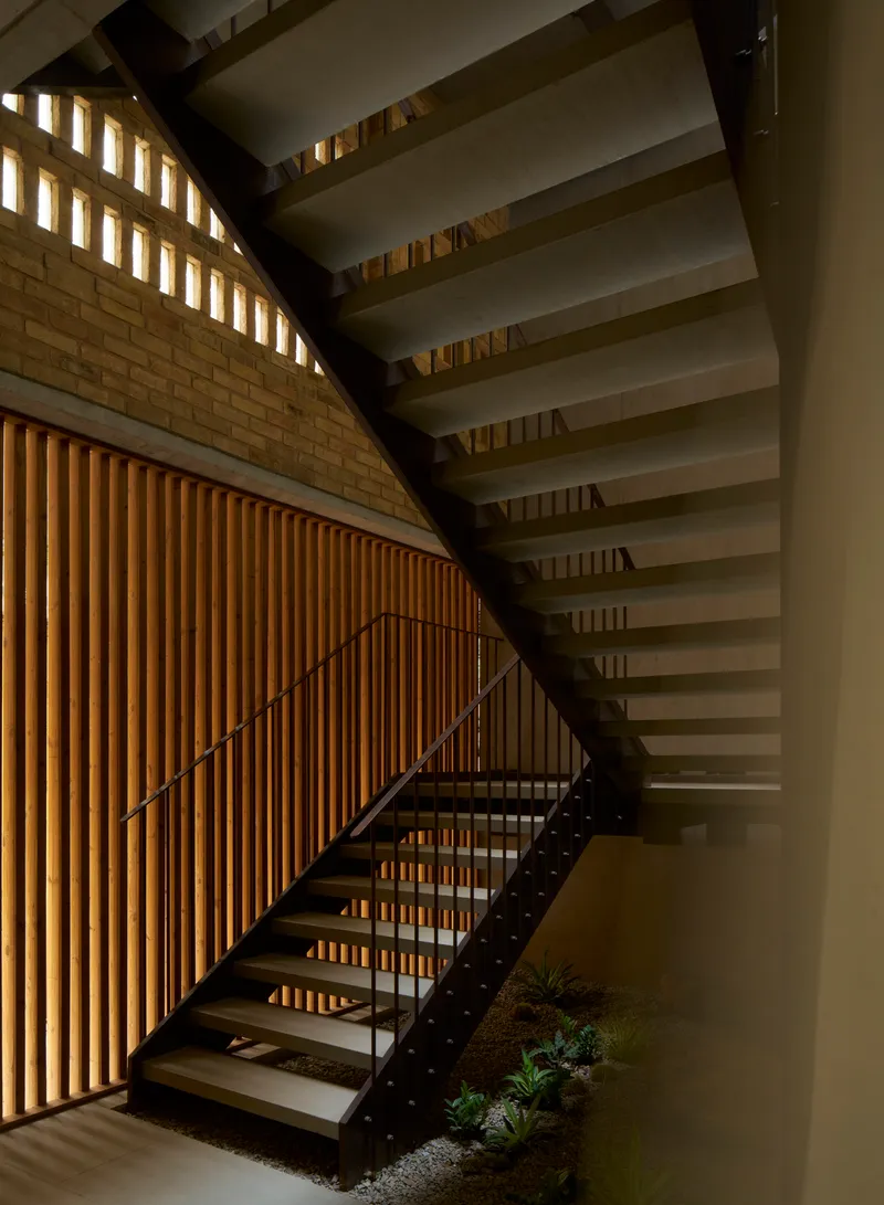 Steel staircase ascending beside vertical timber slat wall with planted bed at base