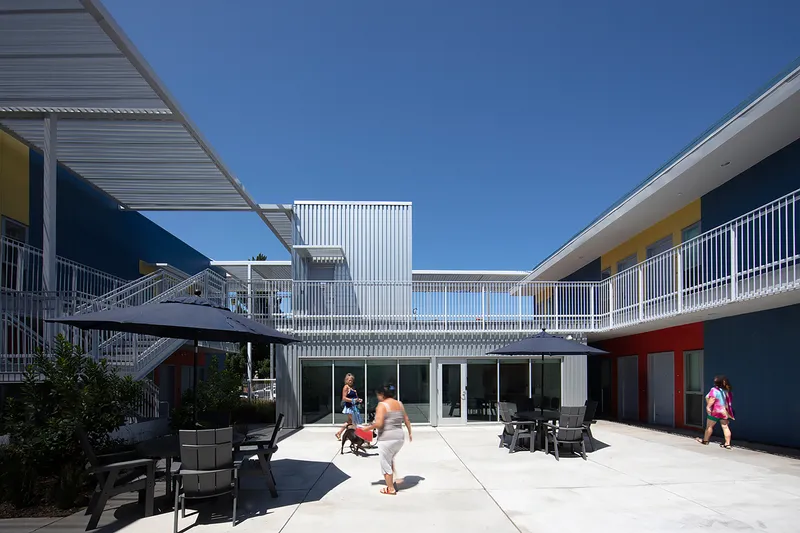 Interior courtyard with white metal railings, staircases, and outdoor seating under bright midday sun