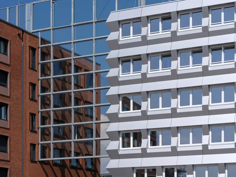 Detail of the white panel facade meeting a glazed curtain wall and adjacent brick building