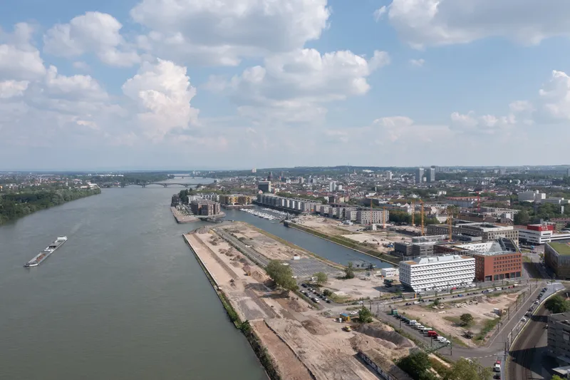 Aerial view of the riverside site with harbor basin and surrounding urban fabric