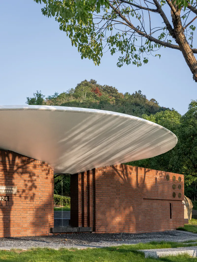 Curved white roof overhang casting shadows on red brick walls with vertical slat screen entrance