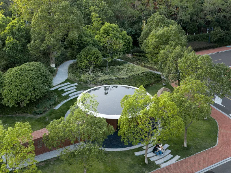 Aerial view of the circular green roof with central oculus and radiating pathways through the landscape