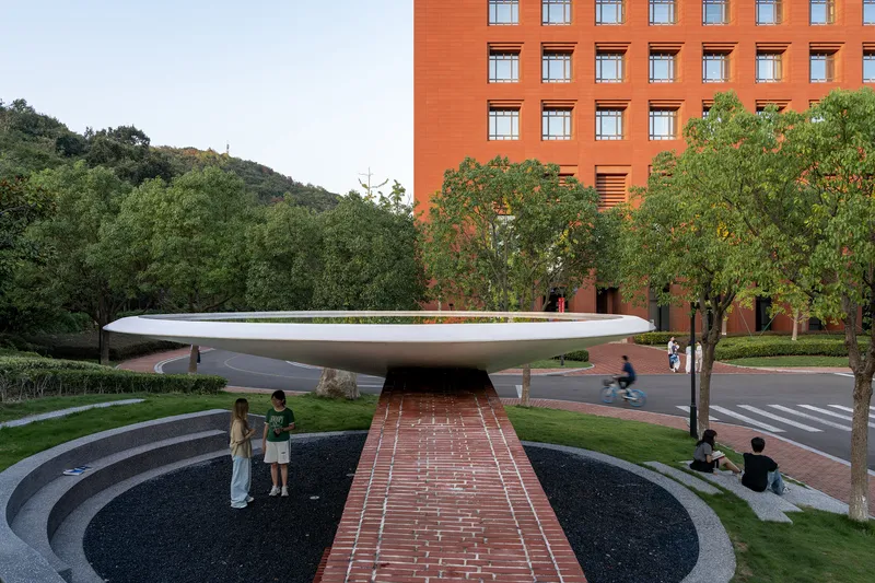 Brick pathway crossing the sunken plaza beneath the hovering white canopy with pedestrians walking by