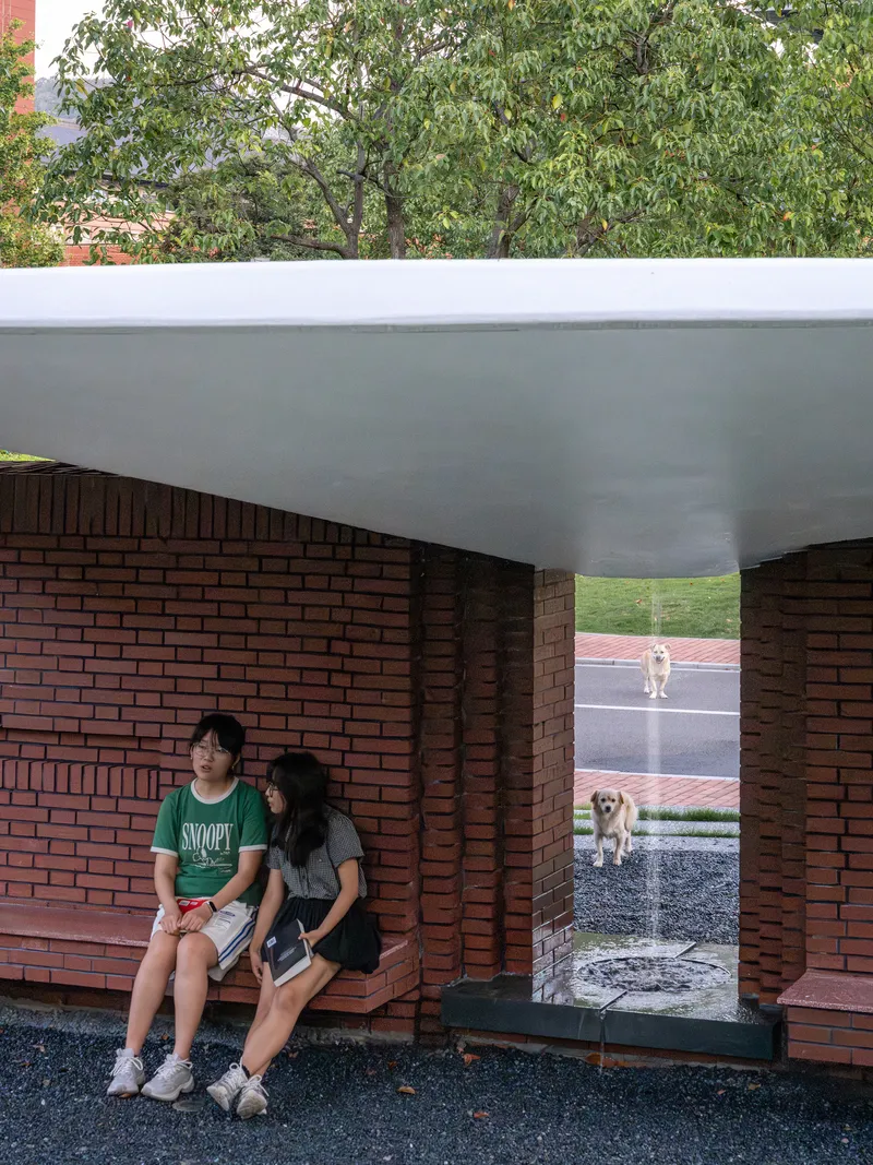 Sheltered seating area with brick benches and columns framing views to the street and passing dogs