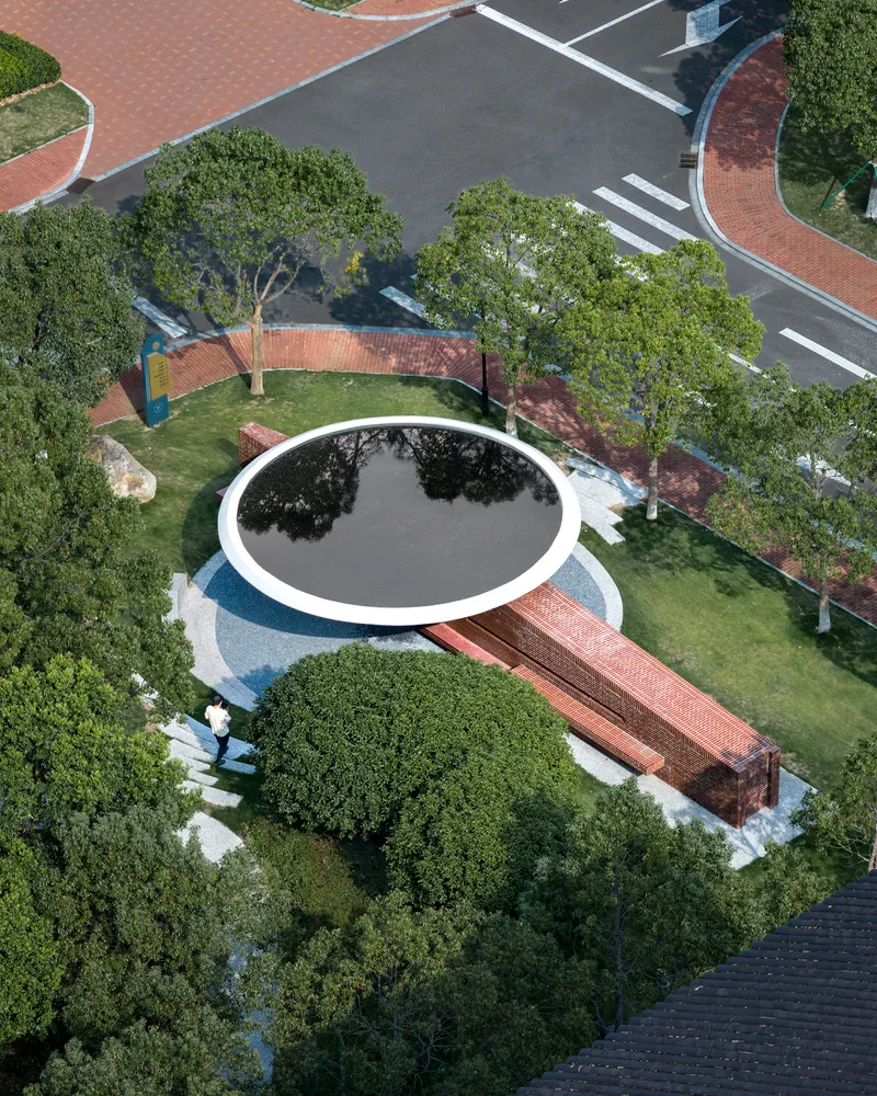 Aerial view of circular reflecting pool surrounded by lawn, brick pavilions and mature trees