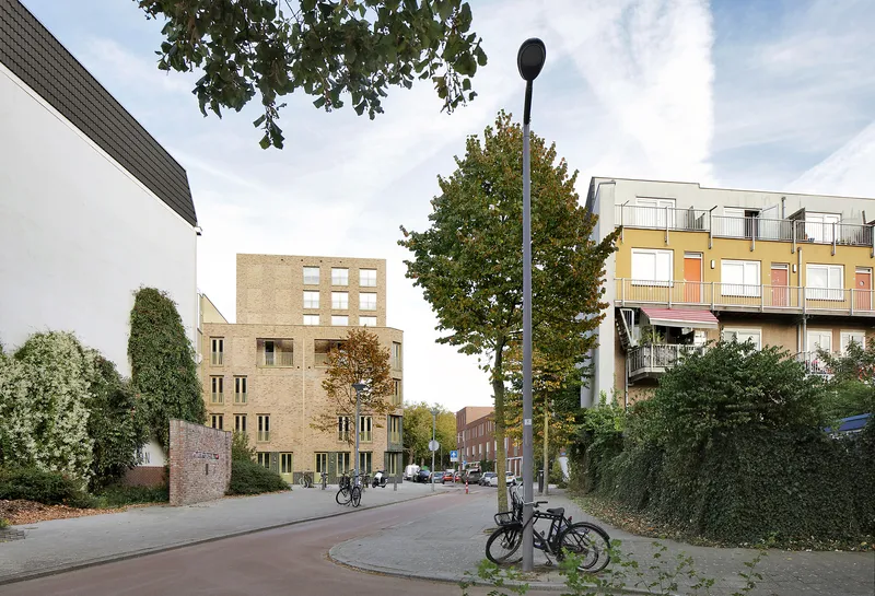 Neighborhood street corner with the brick tower in the background and bicycles parked in autumn leaves