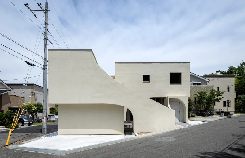 White stucco facade with arched openings at ground level facing a residential street with overhead power lines