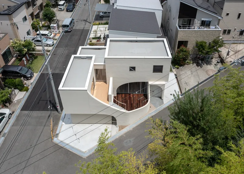 Aerial view of white roof terraces with a curved timber deck nestled among neighboring houses