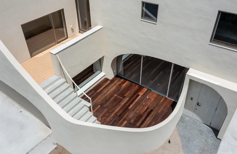 Top view of the curved terrace and staircase showing timber deck and arched glass wall