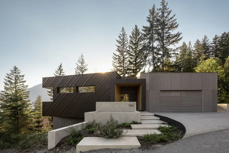 Entry facade with concrete retaining wall, wide steps, and garage clad in charcoal metal panels