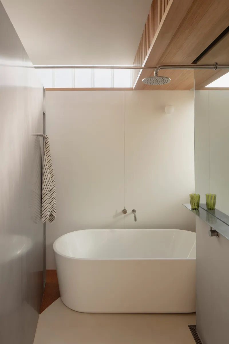 Bathroom with freestanding oval tub beneath a timber-lined soffit and high glazing