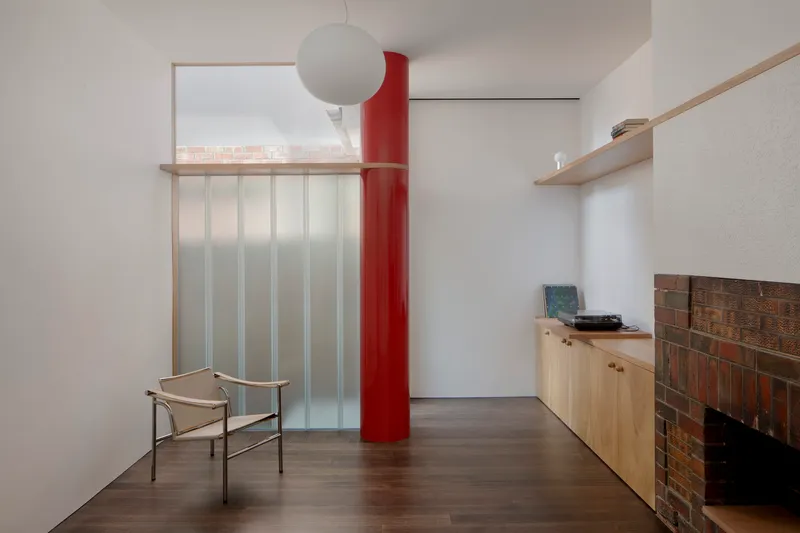 Living room with red cylindrical column, translucent sliding screen and low cabinet beside brick fireplace