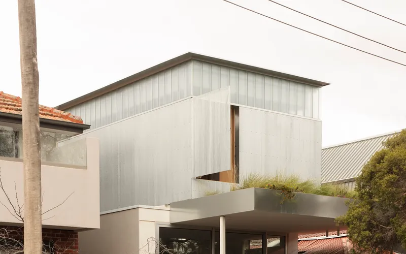 Side elevation of the metal-clad upper volume with narrow vertical window opening beside planted terrace