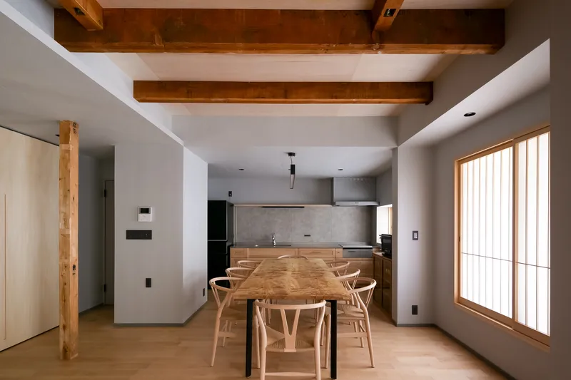 Dining area with exposed timber beams and concrete backsplash beneath a recessed ceiling panel