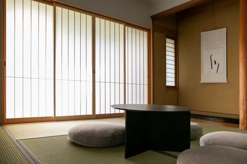 Tatami room with vertical slatted screens and floor cushions around a low black table