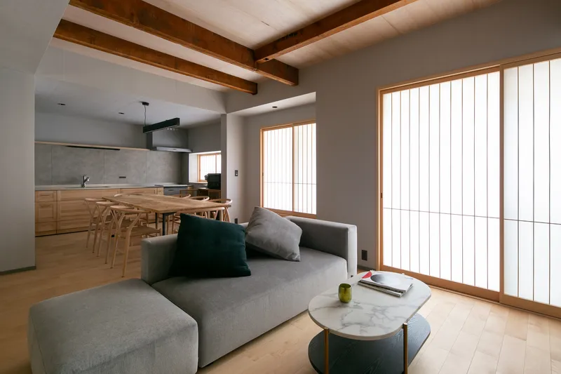 Open living and dining area with exposed timber ceiling beams and vertical slatted screen windows