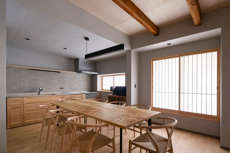 Dining area with timber table and chairs beneath exposed ceiling beams and translucent sliding screens