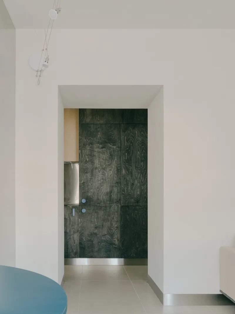Doorway framing a dark green wood-grain door panel with circular metal hardware in white plaster opening