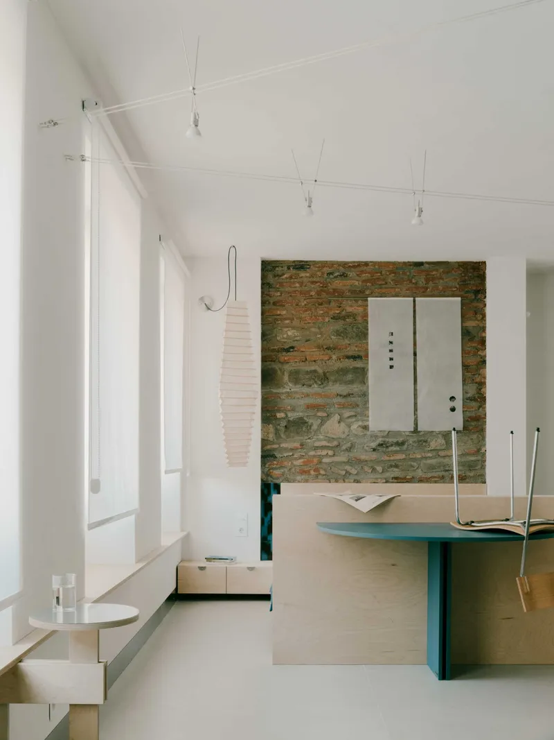 Living area showing exposed brick accent wall with white metal panel and paper pendant lamp overhead