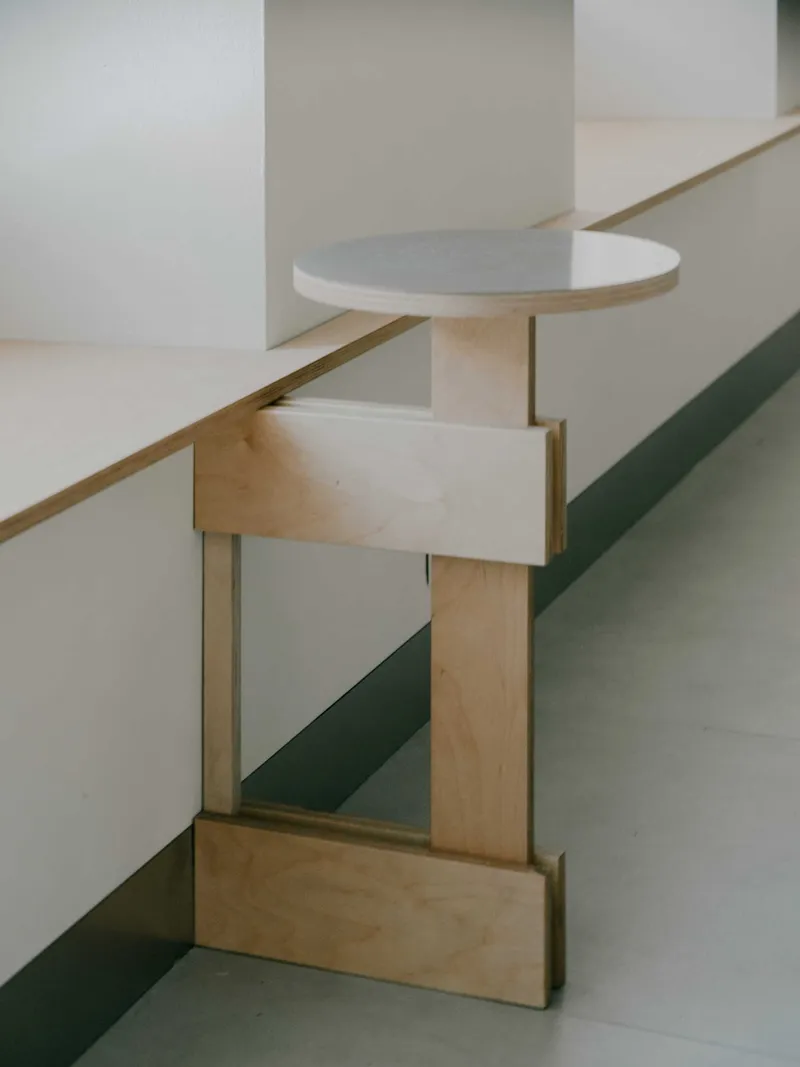 Light wood staircase with rounded handrail platform casting shadows on white walls in soft daylight
