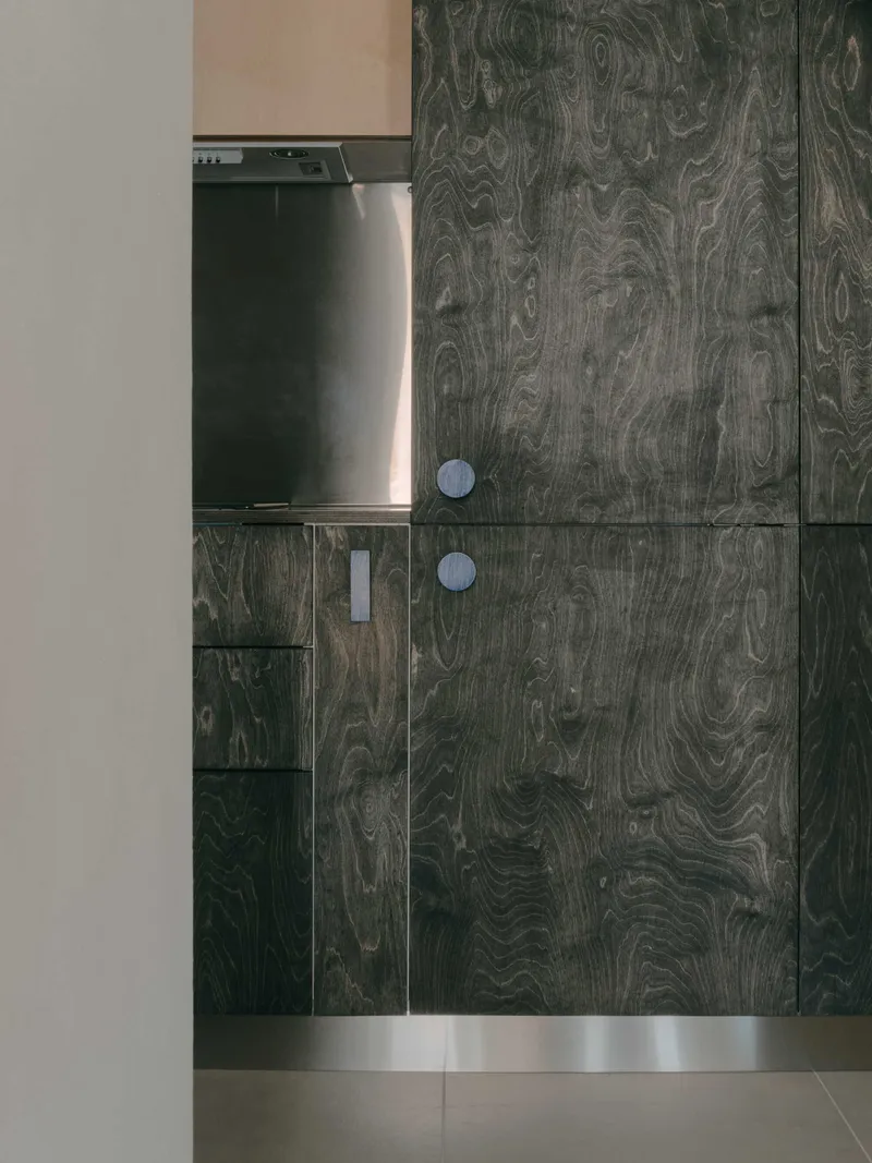 Dark wood grain kitchen cabinetry with circular pulls beside a stainless steel appliance