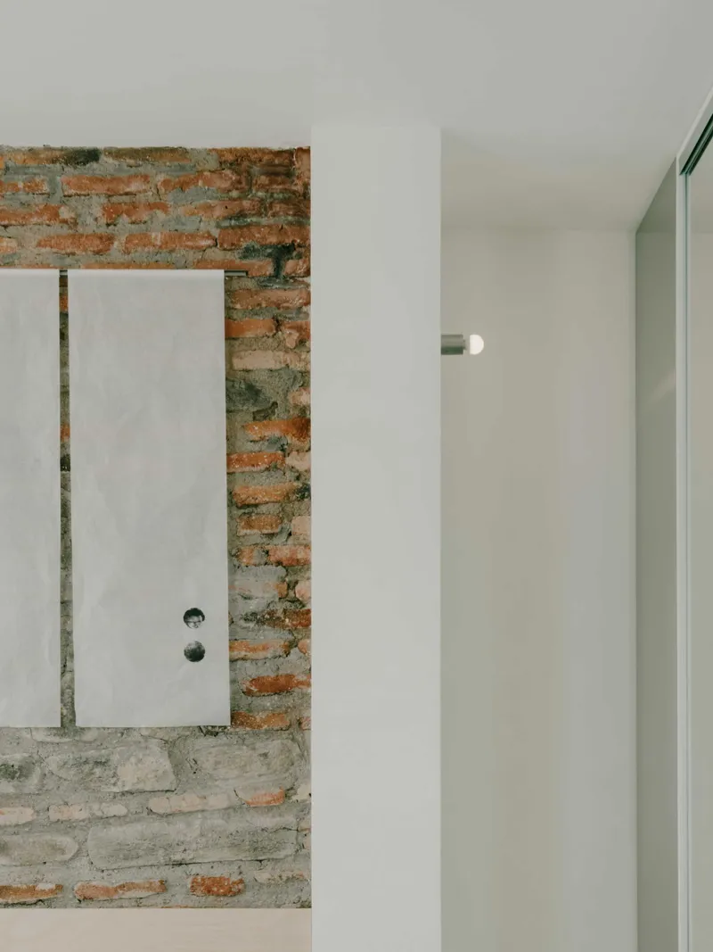 White door with circular hardware set within an exposed brick wall opening