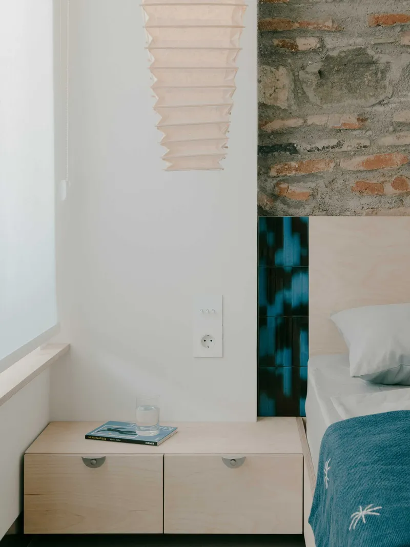Light wood bedside cabinet with semicircular pulls beneath a paper accordion pendant lamp
