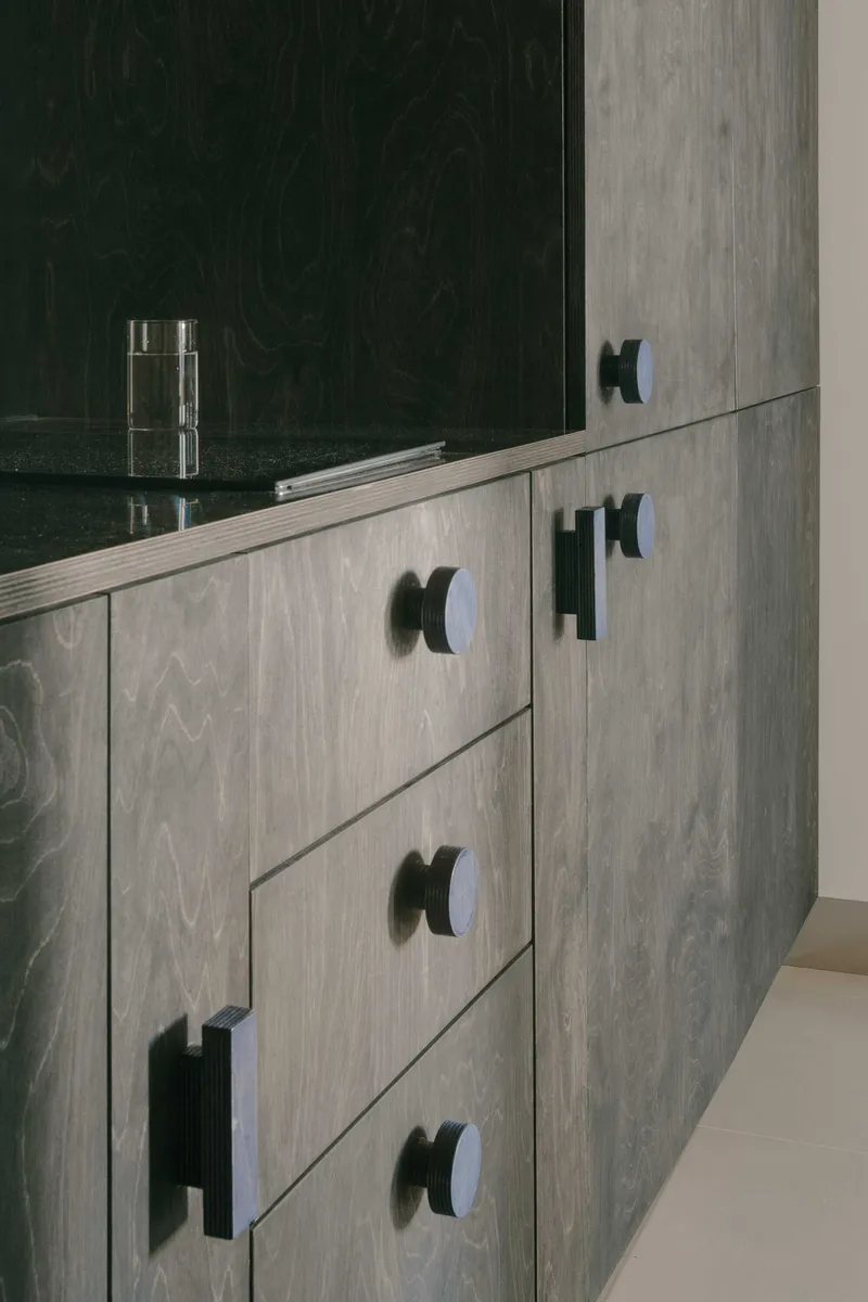 Grey wood veneer drawer fronts with black rounded pulls and stone countertop above
