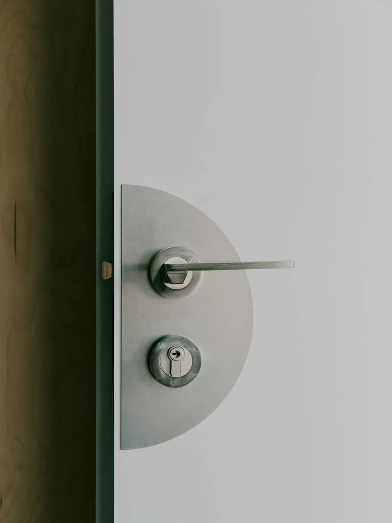 Brushed steel door handle and lock set on a semicircular plate against a white door