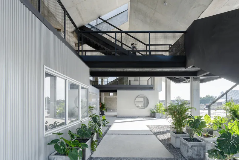 Interior courtyard with black steel staircase, exposed concrete ceiling and planted beds beside a walkway