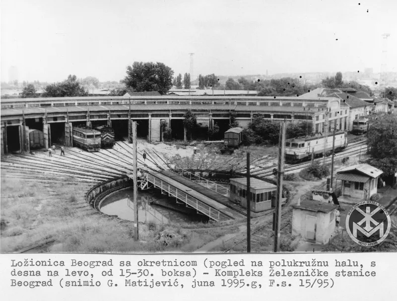 Archival photograph showing a circular rail turntable in front of concrete train sheds and maintenance buildings