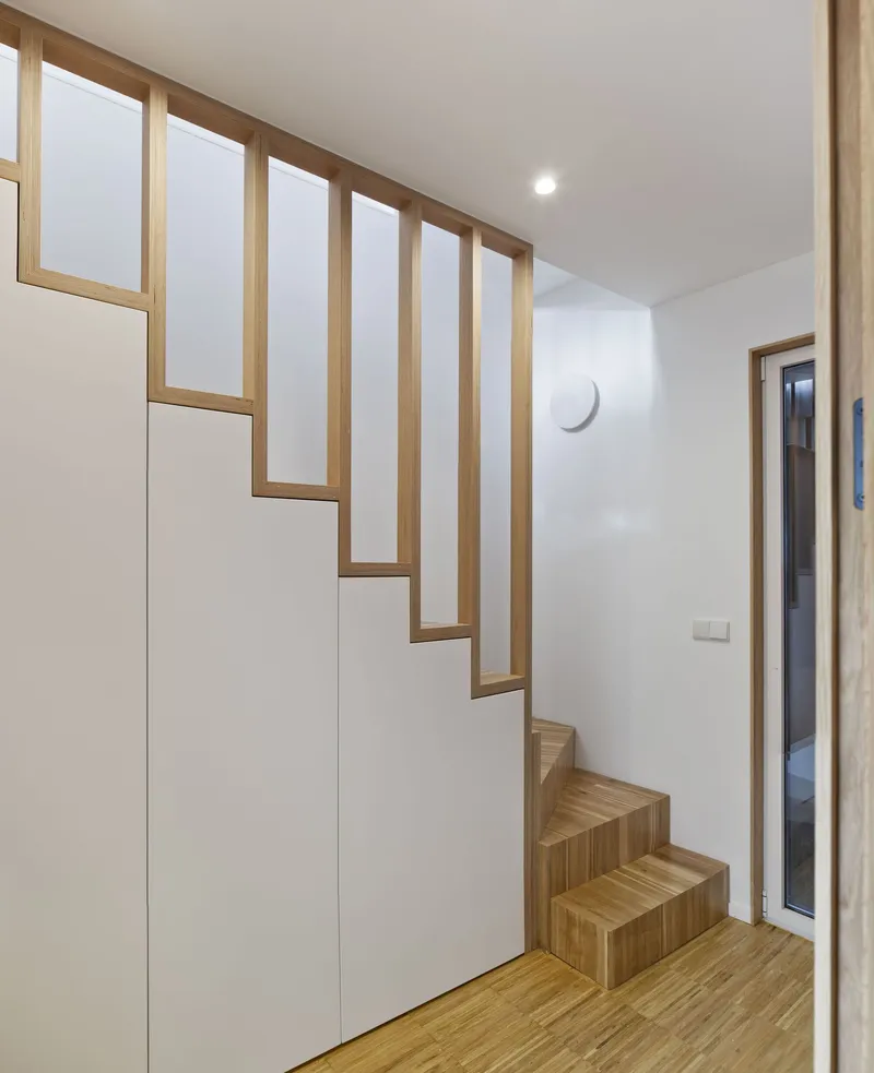 Timber-framed staircase with open risers and integrated storage cabinet along the wall