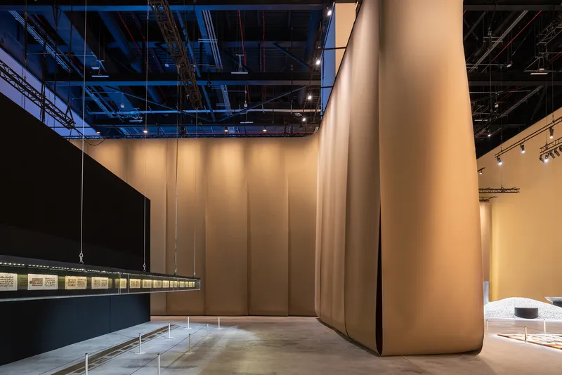 Tall fabric partition panels in cream tones beneath exposed ceiling infrastructure at dusk