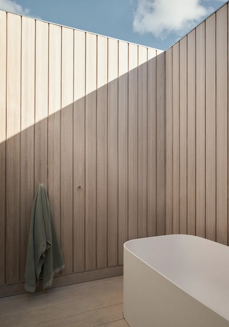 Vertical timber battens meeting at corner with shadow line in afternoon light