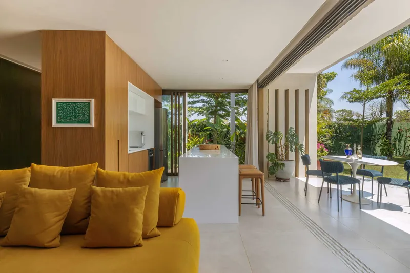Interior opening to covered terrace with vertical slat screens and pool visible beyond palm trees