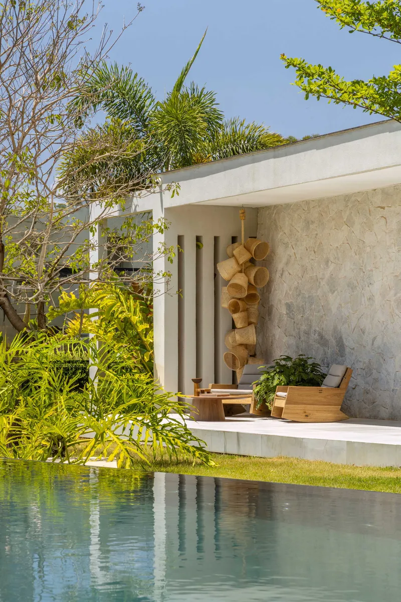 Pool edge with outdoor seating platform framed by vertical screens and tropical landscaping
