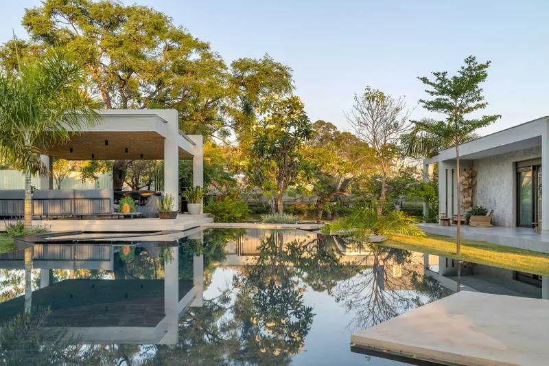 Courtyard pool reflecting surrounding trees and the white-framed pavilion at dusk