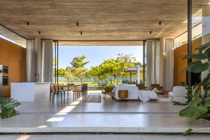 Open-plan living space with timber ceiling and retractable curtains opening to the pool terrace