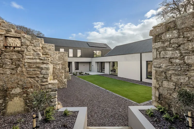 Courtyard framed by preserved stone ruin walls with gravel ground and planted beds