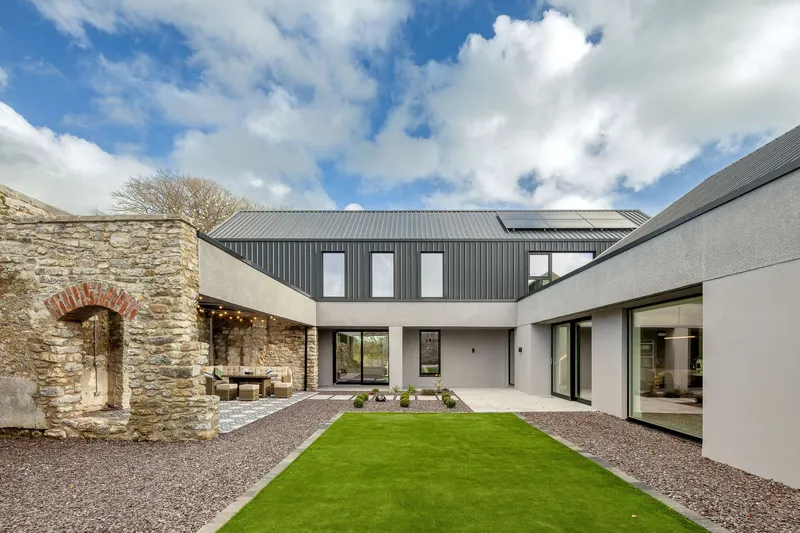 Internal courtyard with stone arch remnant and linked volumes under dramatic clouded sky