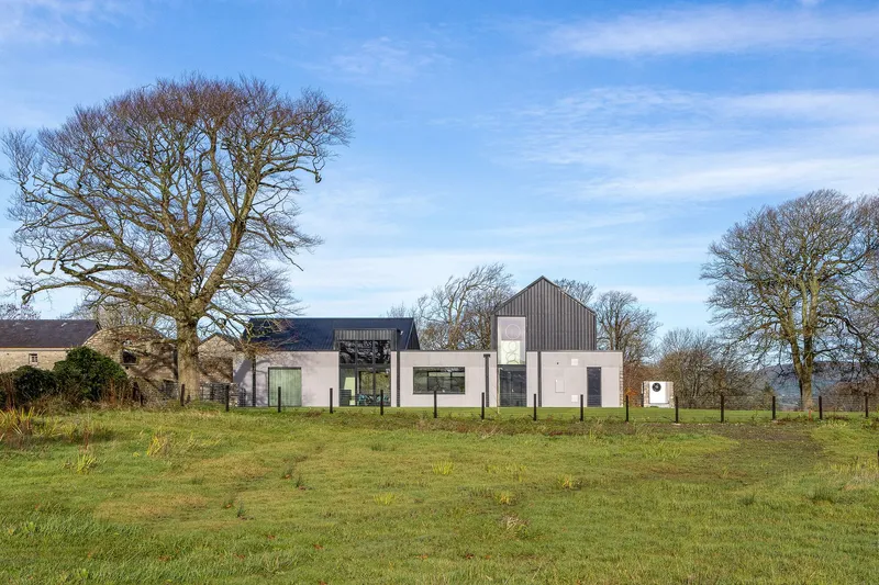 Distant view of the residence among bare winter trees in an open pasture