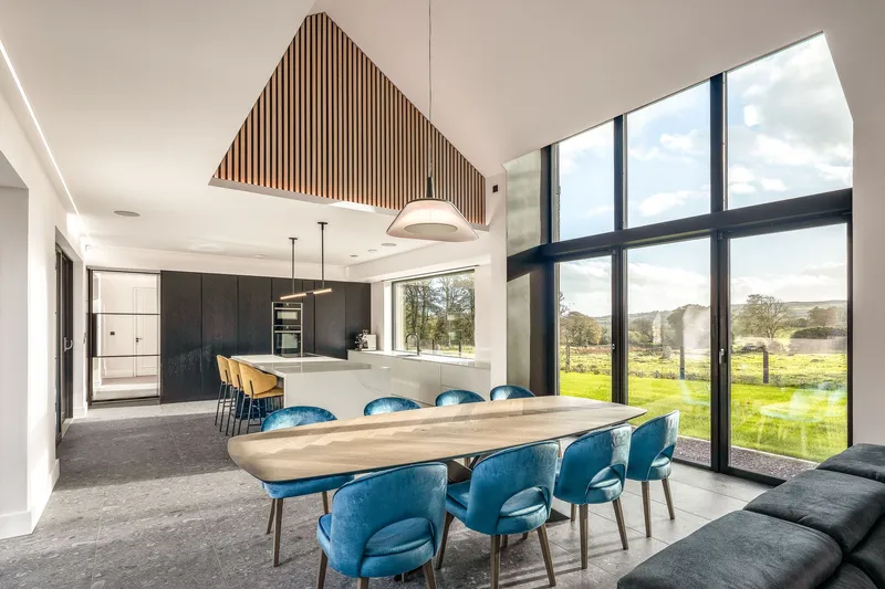 Open-plan dining and kitchen with timber slat ceiling panel and pastoral views beyond