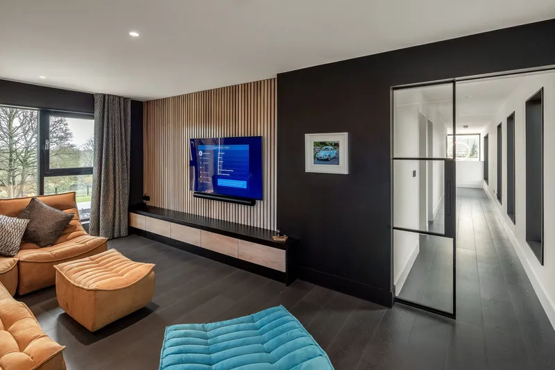 Media room with vertical timber slat wall and steel-framed glass door to corridor