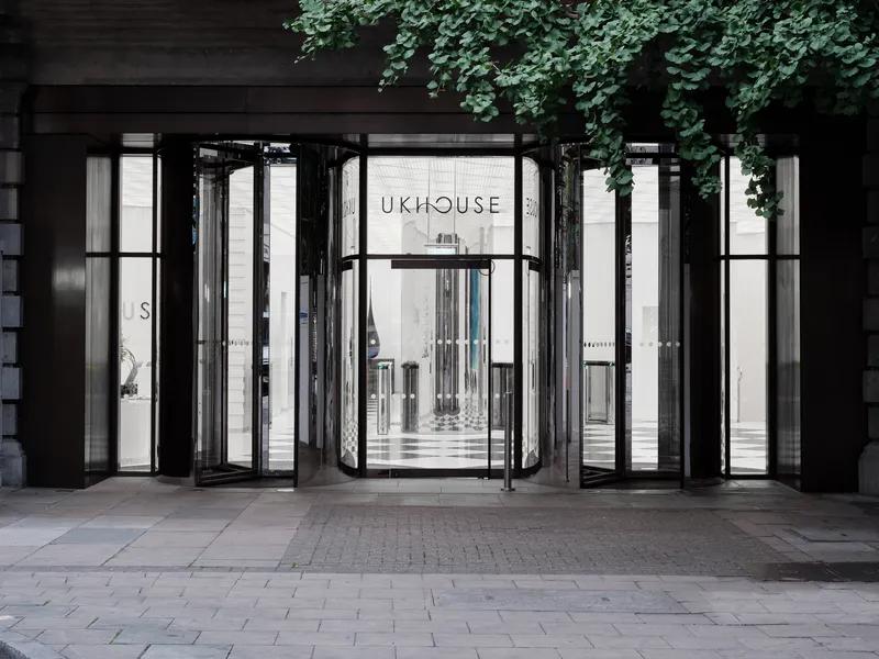 Street view of the glass folding door entrance framed by dark metal and overhanging ivy