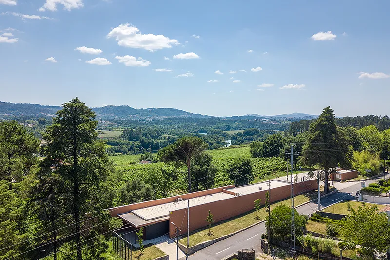 Aerial view of the low terracotta-roofed structure set along a road with vineyards and hills beyond