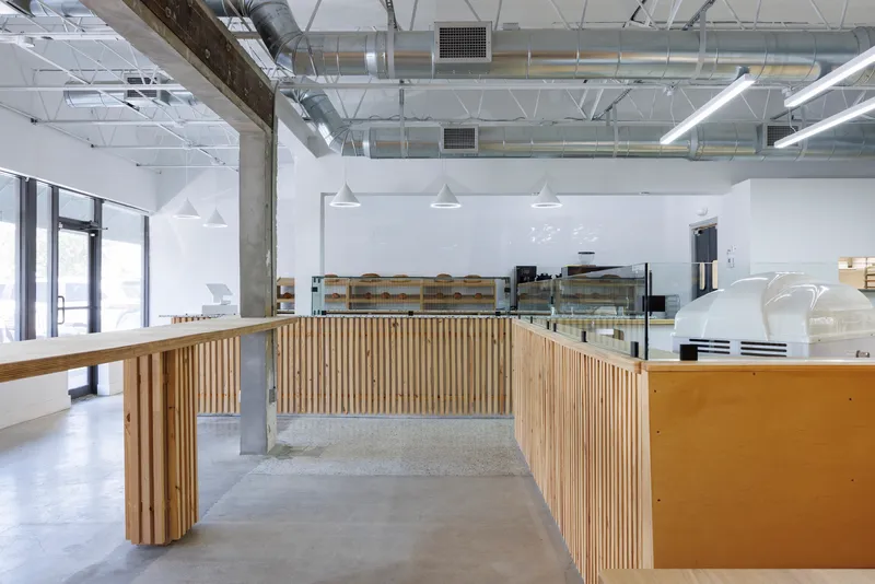 Service counter with vertical timber slat cladding and concrete floor under linear pendant lights