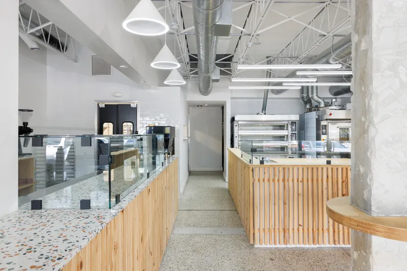 Service corridor between timber slat counters with terrazzo flooring and pendant lighting overhead