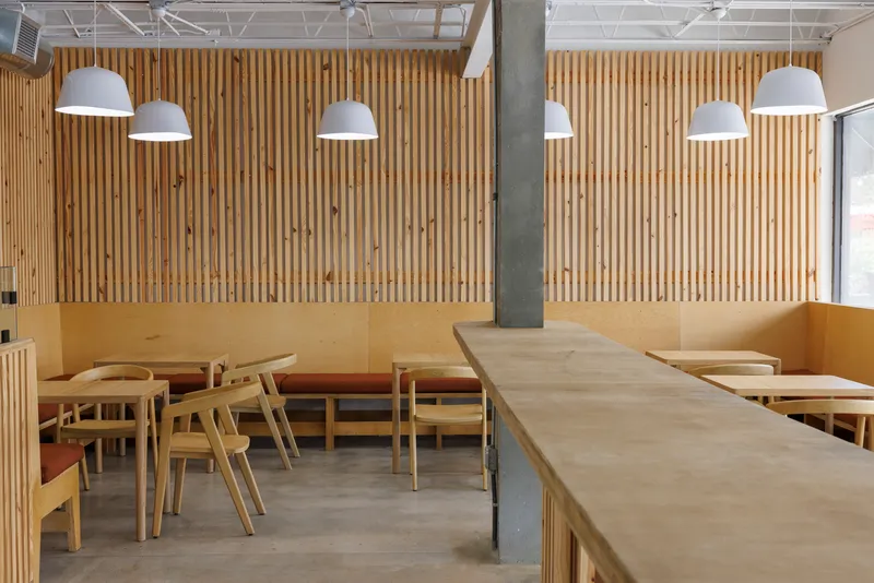 Dining area with banquette seating against vertical timber slat wall and concrete column in foreground
