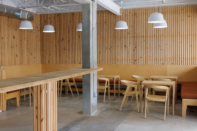 Seating zone with timber tables and chairs arranged around a raw concrete column
