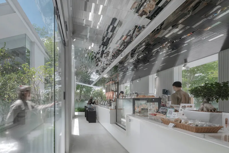 Service counter with bakery display cases under a patterned ceiling with blurred figures walking past